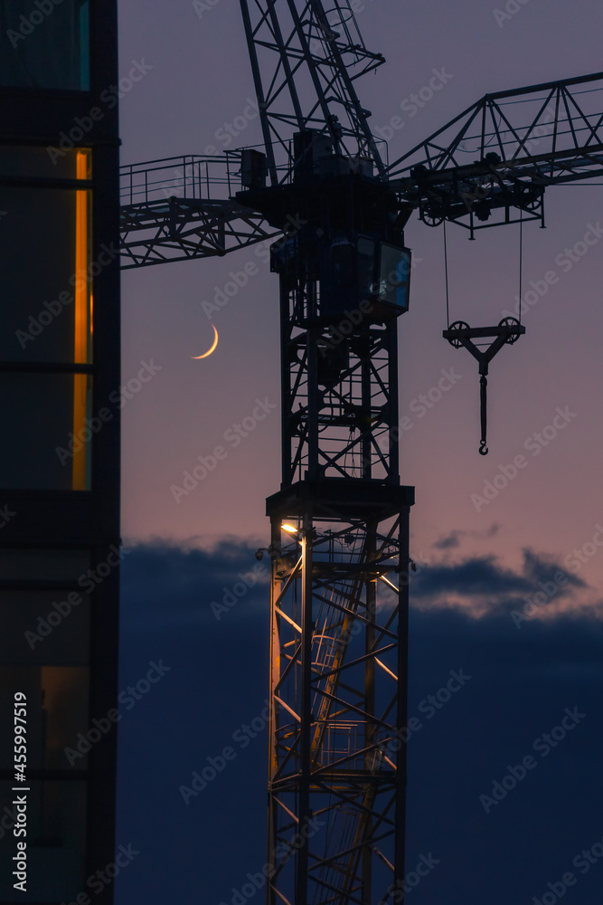 A crescent moon rises behind the silhouette of a building crane. Toronto Ontario