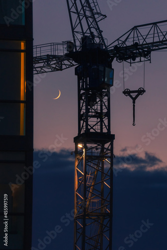 A crescent moon rises behind the silhouette of a building crane. Toronto Ontario