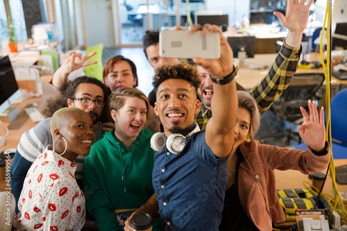 Team taking group selfie with smartphone in office