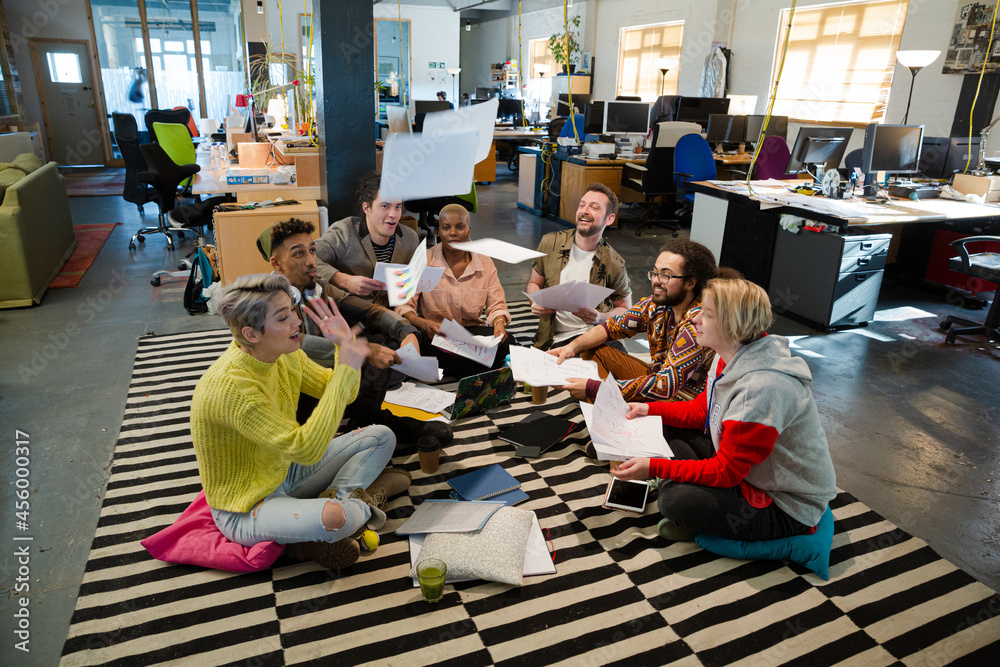 Team sitting on floor, discussing paperwork