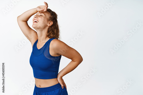 Fototapeta Naklejka Na Ścianę i Meble -  Happy sports woman workout, wipe sweat on forehead and smiling relieved. Fitness girl resting after jogging, finish exercises, white background