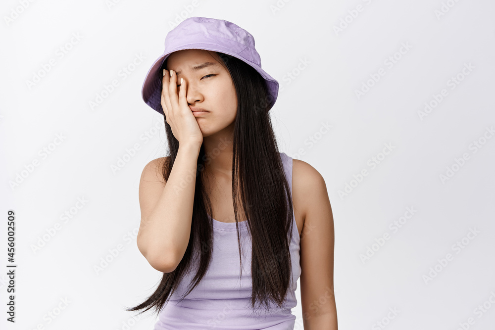 Tired asian girl facepalm, sighing and looking exhausted, annoyed by something, standing against white background Tired asian girl facepalm, sighing and looking exhausted, annoyed by something, standing against white background