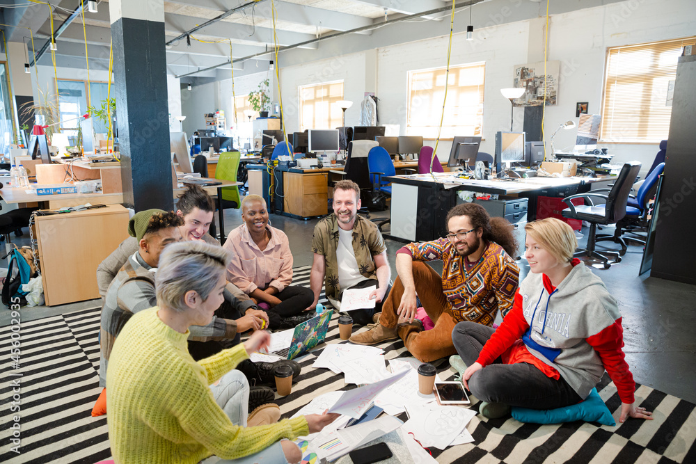 Team sitting on floor, discussing paperwork Team sitting on floor, discussing paperwork