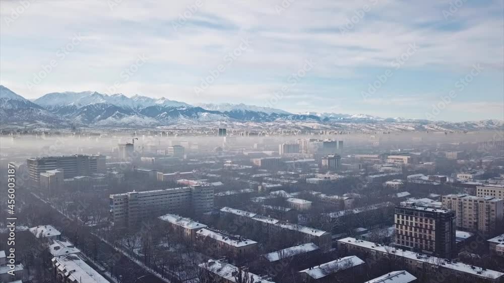 Shooting from a drone over the big city of Almaty. View of many roads, cars, people and large mountains. Places smog and fog. People walk the streets. Beautiful buildings with glass Windows. Trees. Shooting from a drone over the big city of Almaty. View of many roads, cars, people and large mountains. Places smog and fog. People walk the streets. Beautiful buildings with glass Windows. Trees.