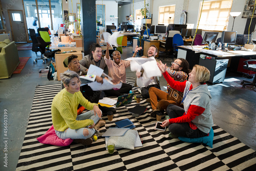 Team sitting on floor, discussing paperwork Team sitting on floor, discussing paperwork