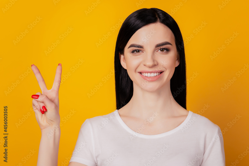 Portrait of attractive nice smiling young lady showing double v-sign gesture isolated yellow color background Portrait of attractive nice smiling young lady showing double v-sign gesture isolated yellow color background