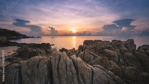 Koh Samui Island, Thailand. Scenic island's dawn view at peaceful bay with sunrise's colorful cloudy sky and stunning textured rock formation foreground. 