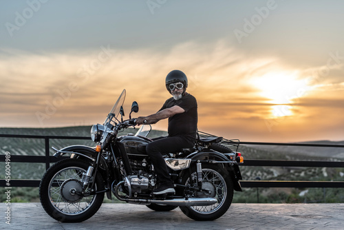 Mature man with sidecar in sunset with her bike