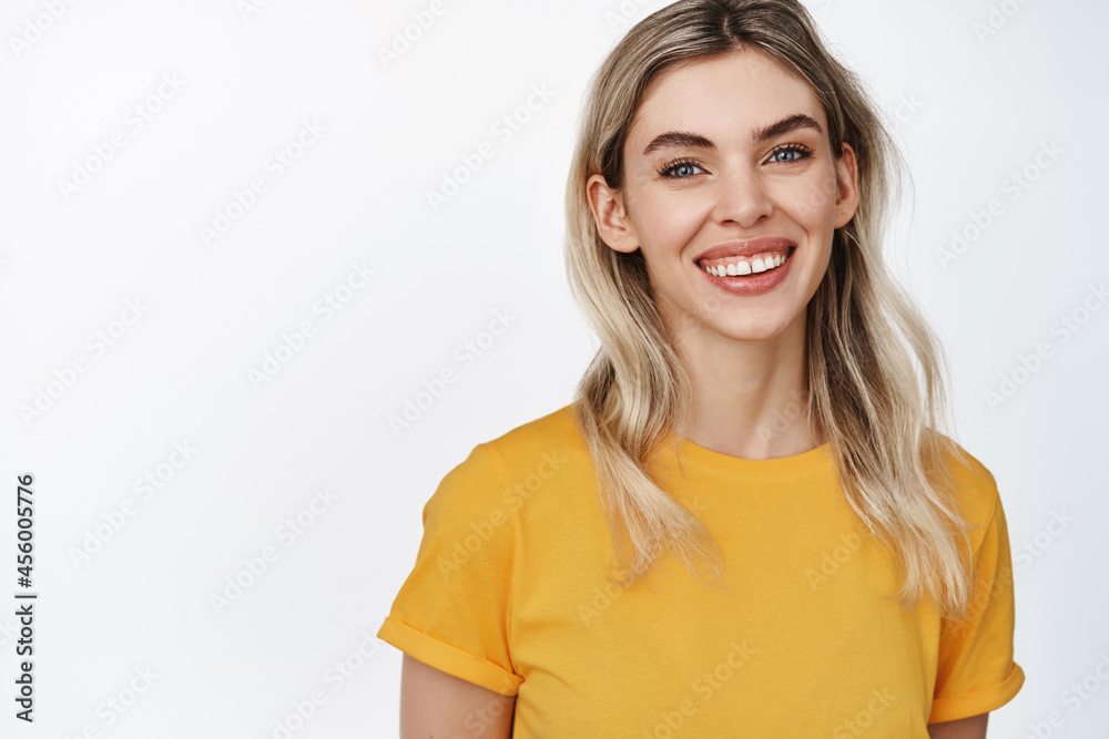 Beauty. Smiling natural girl with happy face expression, looking at camera, wearing yellow t-shirt, standing over white background Beauty. Smiling natural girl with happy face expression, looking at camera, wearing yellow t-shirt, standing over white background