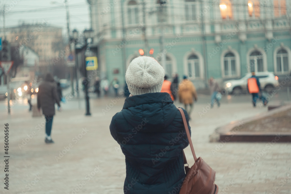 a girl in a winter hat walks around the city