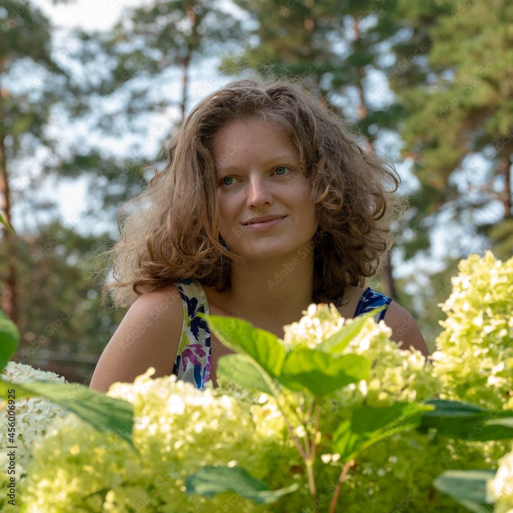 Young woman in the garden among white hydrangea flowers Young woman in the garden among white hydrangea flowers