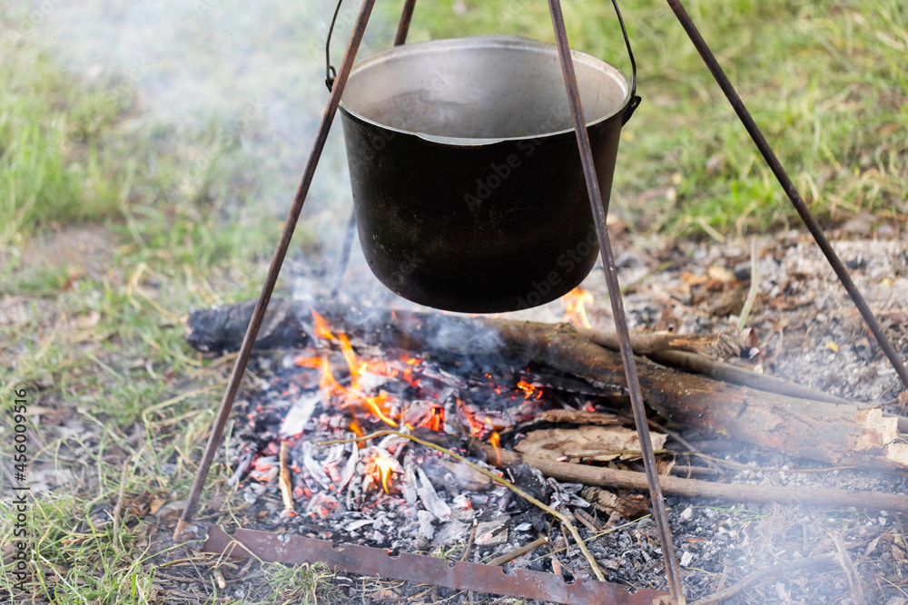 Tourist pot hanging over the fire on a tripod. Cooking in the campaign Tourist pot hanging over the fire on a tripod. Cooking in the campaign