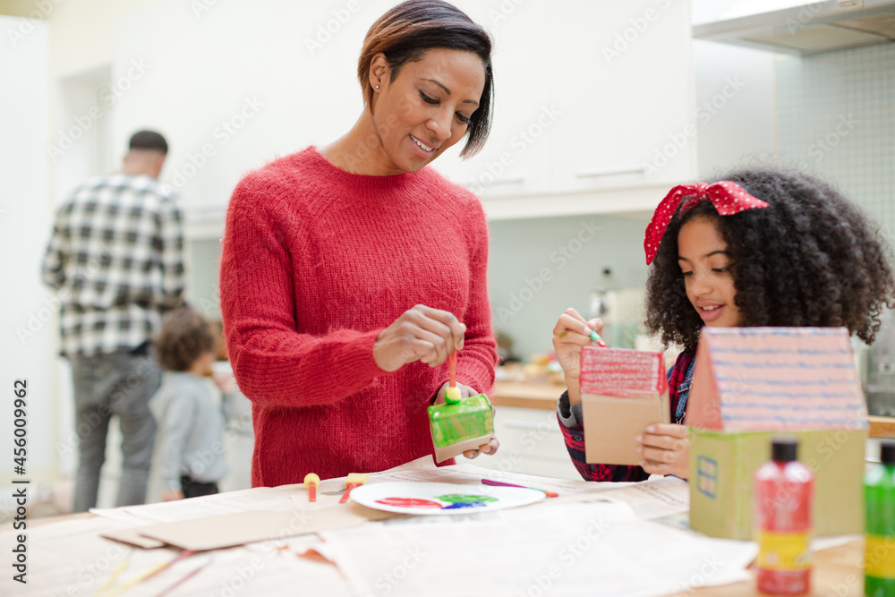 Mother and daughter painting cardboard houses Mother and daughter painting cardboard houses