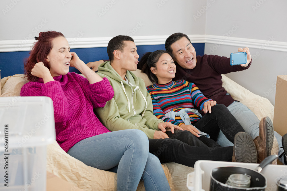 Happy friends taking a break from moving, taking selfie on sofa Happy friends taking a break from moving, taking selfie on sofa
