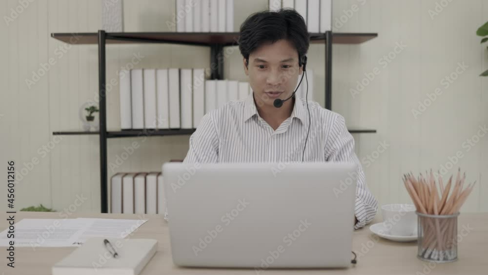 4k video a short-haired Asian man wearing a long-sleeved shirt is interviewing in front of the camera and live streaming at his home or office desk. work and teach from home. social distancing. 4k video a short-haired Asian man wearing a long-sleeved shirt is interviewing in front of the camera and live streaming at his home or office desk. work and teach from home. social distancing.