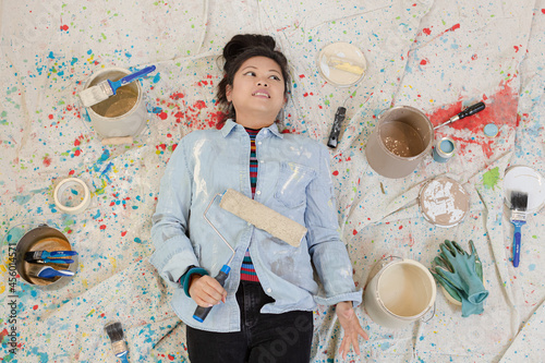 Woman taking a break from painting, laying on dropcloth among paint cans photo