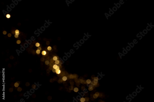 Golden blurred bokeh lights on black background. Glitter sparkle stars for celebrate