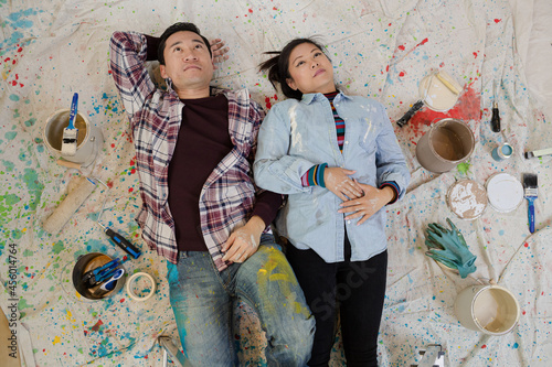 Happy couple relaxing, taking a break from painting, laying on dropcloth among paint cans photo