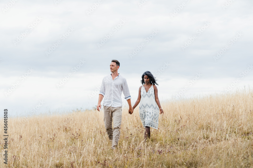 Multiracial couple holding hands in countryside field Multiracial couple holding hands in countryside field
