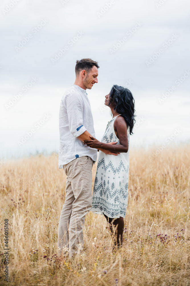Multiethnic couple embracing on meadow in countryside Multiethnic couple embracing on meadow in countryside