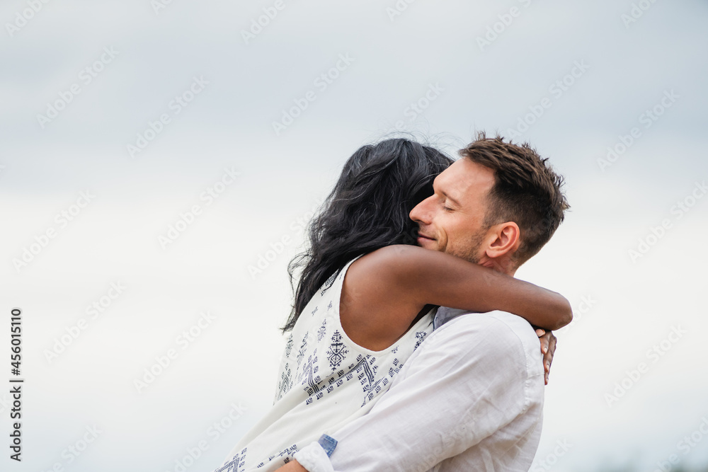 Multiethnic couple embracing on meadow in countryside Multiethnic couple embracing on meadow in countryside