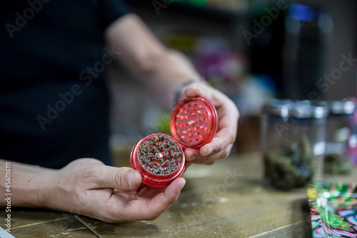 Faceless man with dry marihuana in grinder photo