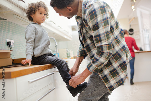 Father putting shoes on son