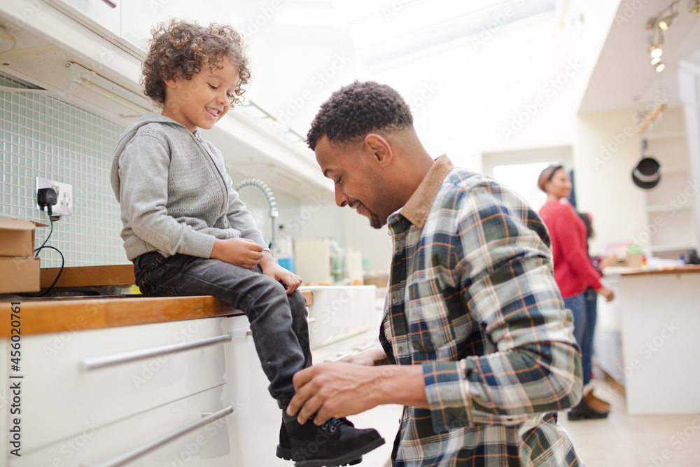 Father putting shoes on son Father putting shoes on son