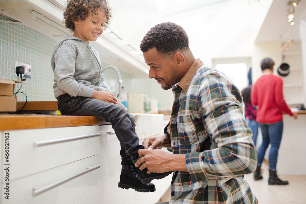 Fototapeta premium Father putting shoes on son