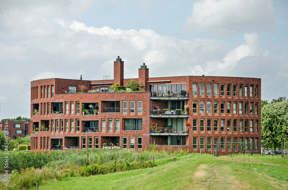 Zwolle, The Netherlands, August 4, 2021: residential building with red brick facades and a circular floor plan in a green environment