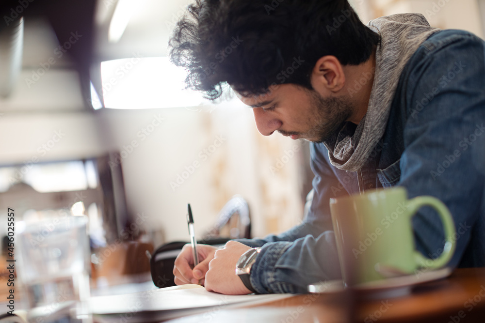 Focused young male college student studying in cafe Focused young male college student studying in cafe