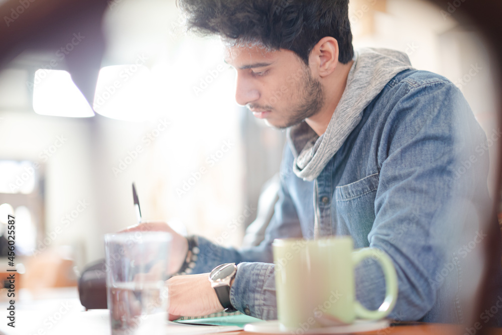 Focused young male college student studying in cafe Focused young male college student studying in cafe
