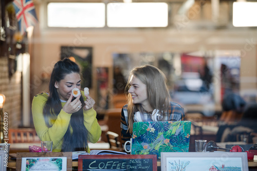 Young female college students studying, eating dessert at cafe window