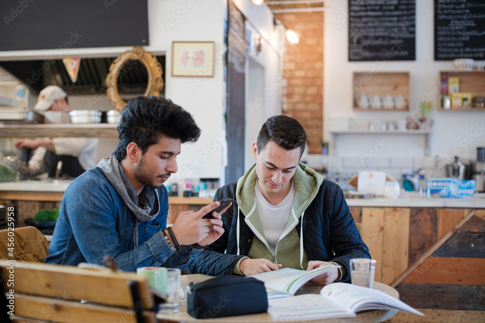 Portrait confident young male college students studying at cafe table Portrait confident young male college students studying at cafe table
