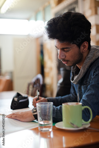 Portrait confident young male college student studying in cafe