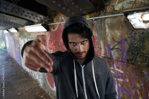 Portrait menacing young man gesturing finger gun in urban tunnel