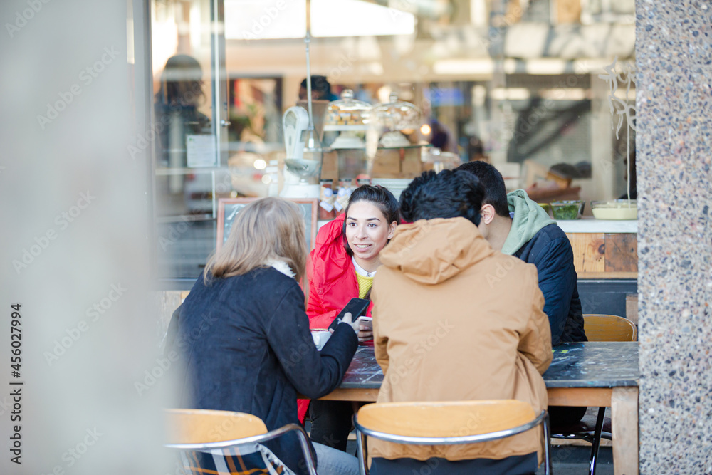 Young adult friends talking at sidewalk cafe Young adult friends talking at sidewalk cafe