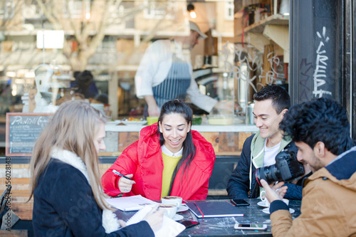 Young adult friends talking at sidewalk cafe