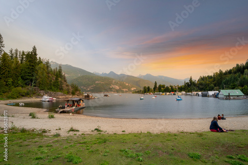 Sunset at the sandy beach of Kaslo Bay on Kootenay Lake in the rural village of Kaslo, BC Canada, with boats and the shipyard in view. photo