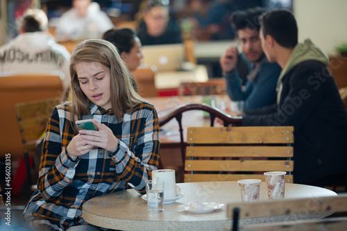 Smiling young woman using smart phone in cafe