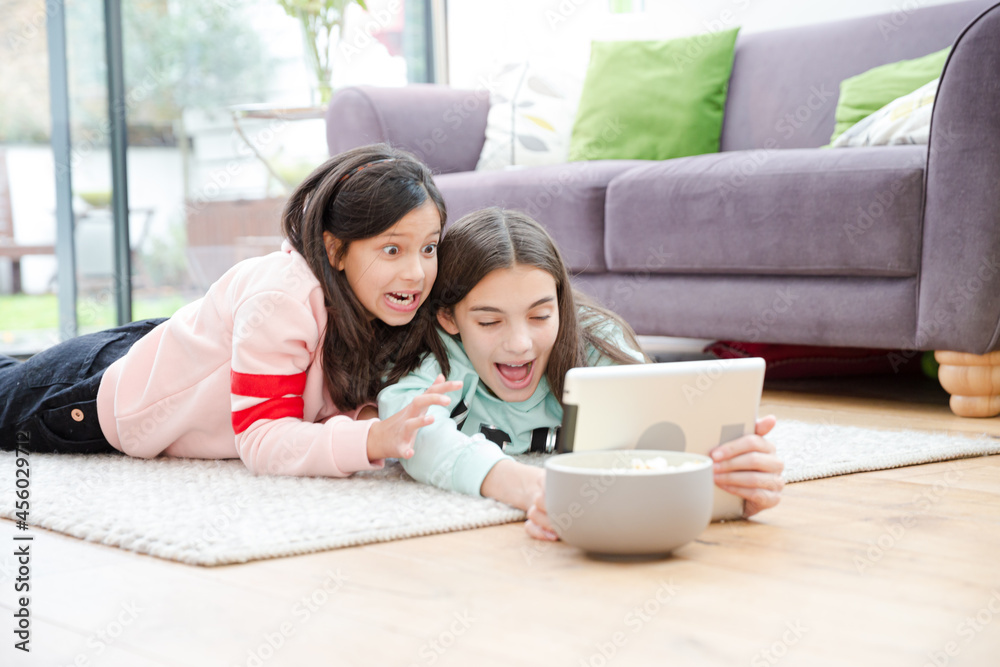 Girls taking selfie with digital tablet on living room floor