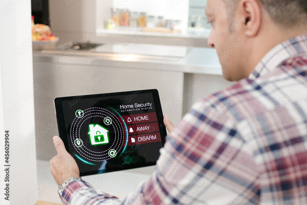Man setting smart home alarm system from digital tablet on living room sofa  Photos | Adobe Stock