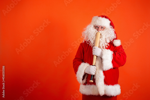Angry Santa Claus with a baseball bat on an orange background.
