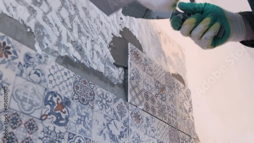 The builder glues the tiles to the wall