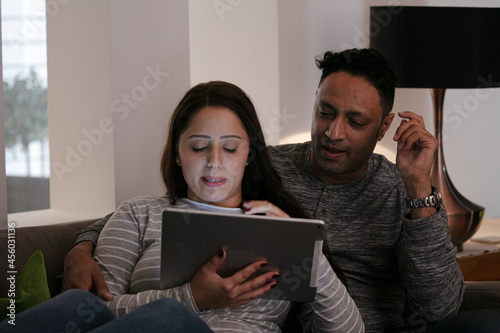 Couple relaxing, using digital tablet on living room sofa