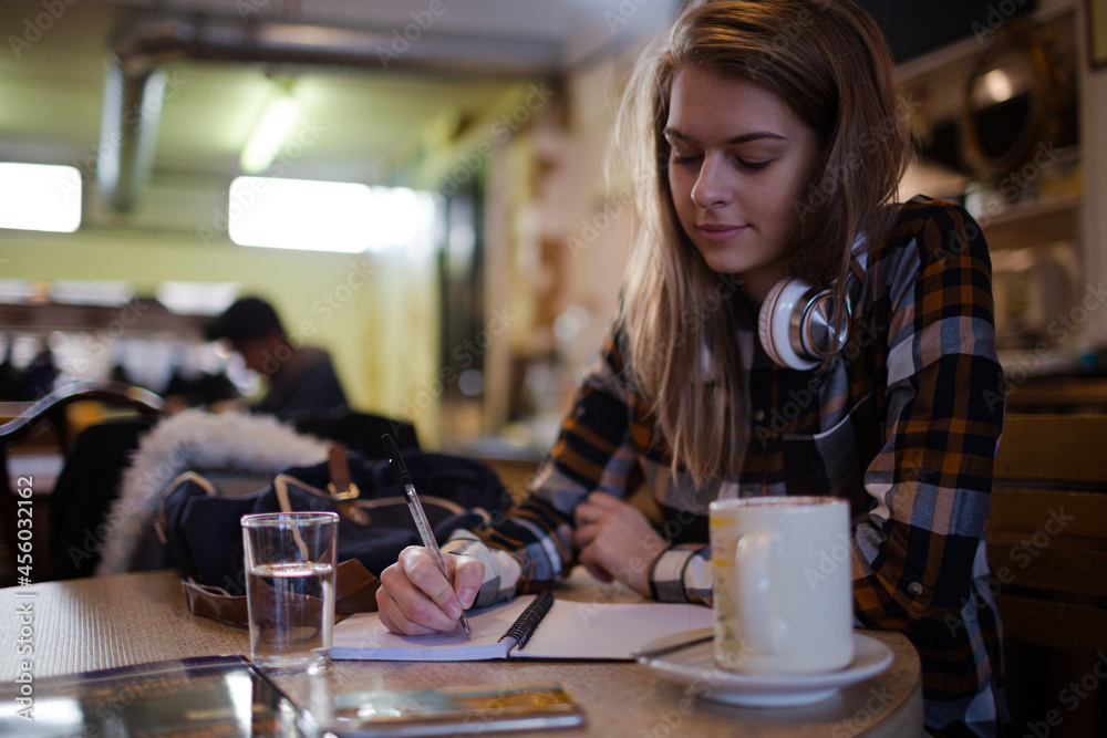 Portrait confident young female college student studying at cafe table