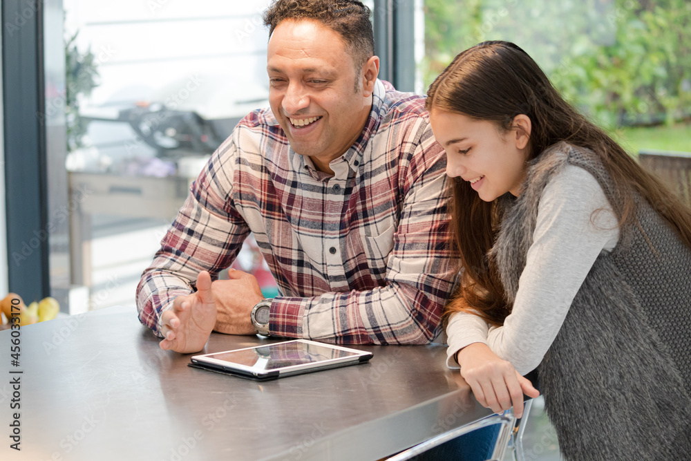 Smiling father and daughter using digital tablet at kitchen counter Smiling father and daughter using digital tablet at kitchen counter