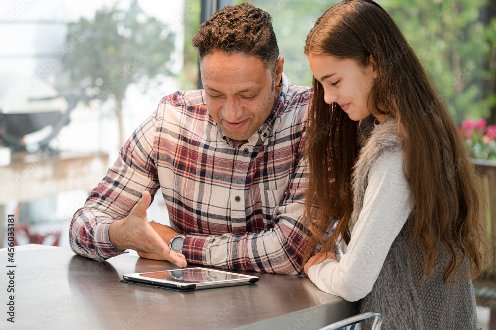 Smiling father and daughter using digital tablet at kitchen counter Smiling father and daughter using digital tablet at kitchen counter