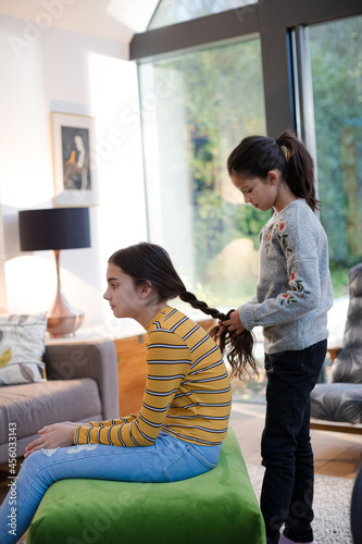 Portrait happy, affectionate sisters plait braid at home