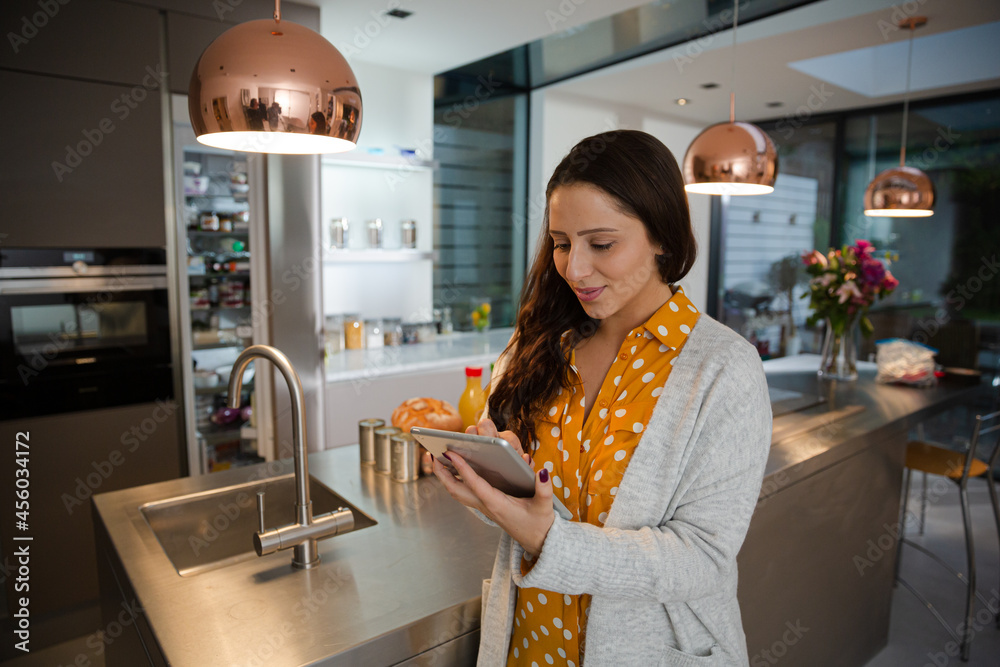 Woman with digital tablet at refrigerator in kitchen Woman with digital tablet at refrigerator in kitchen